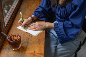 Concentrated woman writing in notepad in cafe