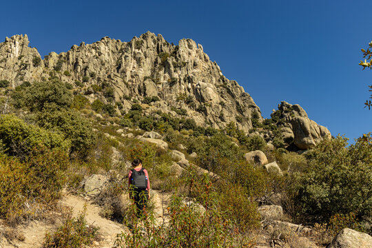 Woman walking at sunset on the Sierra de la Cabrera trail leading to the peak of Cancho Gordo.