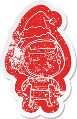 cartoon distressed sticker of a confident astronaut wearing santa hat