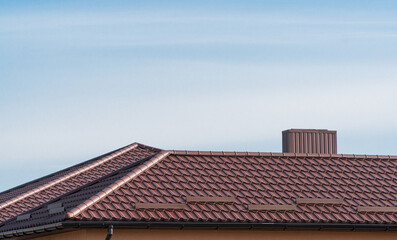 Fototapeta na wymiar Roof of a house with modern metal roof tiles. Brown metal roof of a modern new house