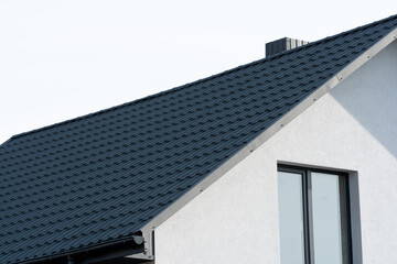 Fototapeta na wymiar The dark-colored roof of a new residential house. Roof covering with steel tiles