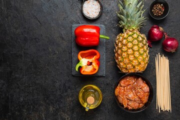 Prepared ingredients for skewers with chicken, pineapple and sweet pepper on a black concrete background. Step by step recipes, cooking.