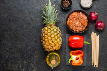 Prepared ingredients for skewers with chicken, pineapple and sweet pepper on a black concrete background. Step by step recipes, cooking.