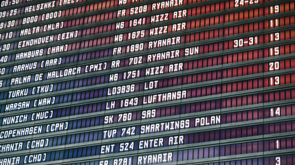 Departures board at an international airport terminal with European flight times and carriers