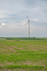 Modern wind turbine renewable energy on agricultural field during cloudy day