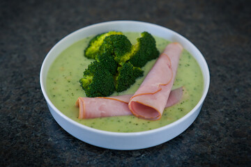 ready to eat - a fresh broccoli cream soup with ham in a white bowl