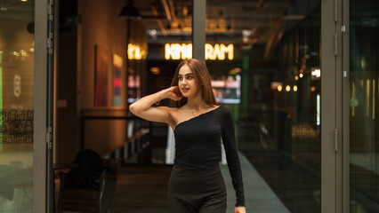 Beautiful happy elegant girl in fashion black clothes with a top and trousers walks in the mall