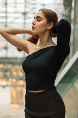Stylish beautiful young elegant woman in fashion black clothes with trousers and a top in an office building