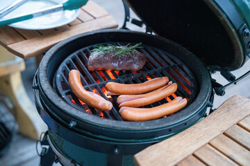 preparing food - grilled venison meat with rosemary and frankfurter on the charcoal grill on the...