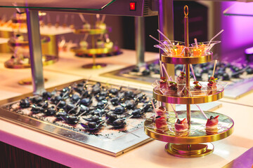 Beautifully decorated banquet catering table with variety of different food snacks, sandwiches, croissants and appetizers on a party event or celebration, delicatessen setting, coffee break