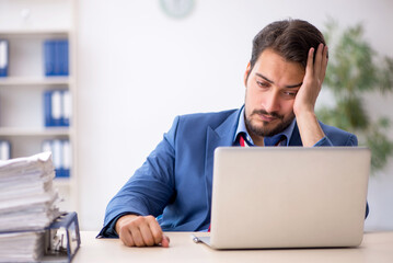 Young male employee unhappy with excessive work in the office