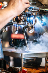 Barista makes coffee in a coffeeshop. Cup of cappuccino or latte in the making.