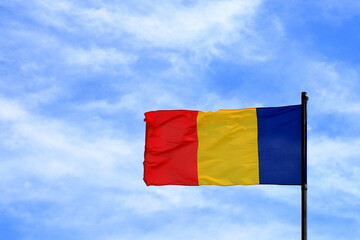 Flag of Romania, Blue yellow red Romanian national flag flies in wind in blue sky