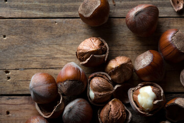 Cracked and unbroken shelled hazelnuts on a wooden background.