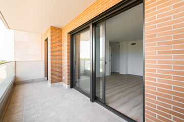 Side view of terrace opening after the large panoramic windows in luxury apartment of new building made of red brick and black metal frames. Concept of open air zone in the house