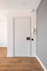 Entrance closed white wooden door to the apartment. Next to the door on the wall there is an intercom handset to allow guests to enter the entrance. On the door there is a key lock.