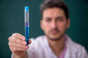 Young male chemistry teacher sitting in the classroom