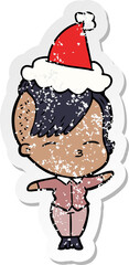 distressed sticker cartoon of a squinting girl wearing santa hat