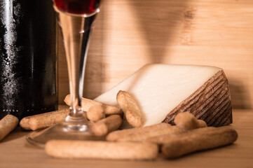 una botella de vino tinto con una copa y maridaje de queso