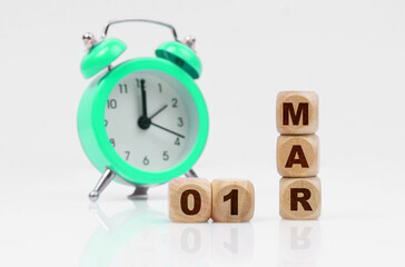 On a white background, a green alarm clock and a calendar with the inscription - March 1