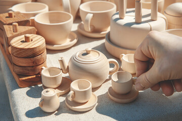 Fototapeta na wymiar hand takes the cup. wooden teapot with cups. various wooden toys as a gift, eco-friendly and safe handmade products for the development and education of children