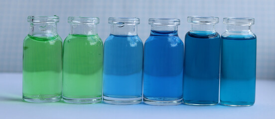 Colored organic substances of green and blue colors in glass jars.