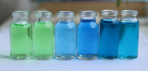 New types of colored vaccines of green and blue colors in glass jars.