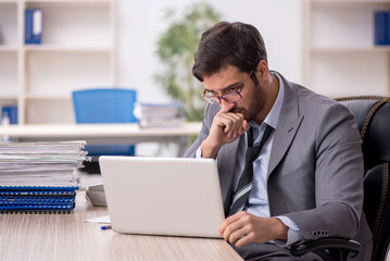 Young male employee and too much work in the office