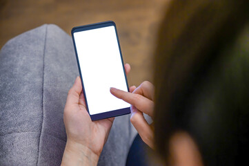 A woman sits in a chair with a smartphone in her hands. Blank mobile phone screen for graphic display montage.