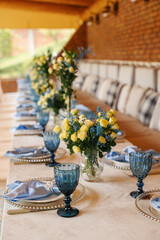 Birthday table decor. Blue glasses and napkins. Flowers on the table.