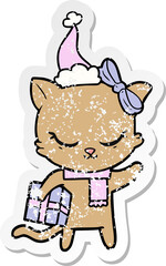 cute distressed sticker cartoon of a cat with present wearing santa hat
