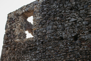 The ruins of the walls of the old castle on the background of the forest and the sky