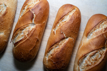 Long brown baked baguette buns on a wooden board
