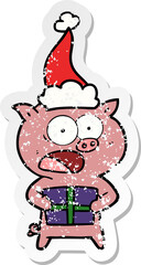 distressed sticker cartoon of a pig with christmas present wearing santa hat