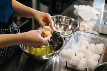 Close up. A cook in the kitchen of a cafe or bakery. Female hands break eggs for dough.