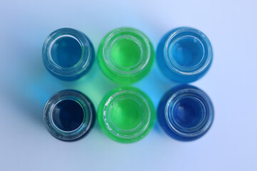 Opened glass jars with blue and green dyes. View from above.