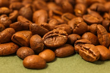 Fotobehang gros plan sur des grains de café posés sur un fond vert kaki, vue de dessus   © Emma