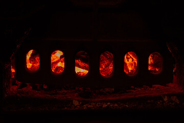 Dark abstract background of furnace door in darkness with red burning coals