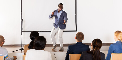 Expressive male lecturer speaking at corporate motivational coaching and training conference