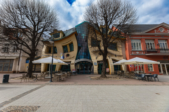 Sopot, Poland - April 2022: "Krzywy Domek" unusual commercial building with a curved structure housing shops, restaurants and cafes with outdoor seating