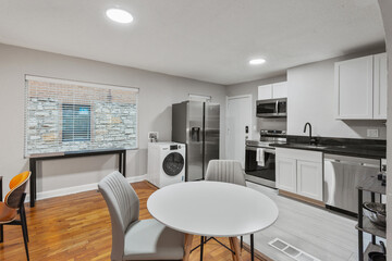 White apartment with wide open spaces, hardwood flooring and modern furniture. Used as a short term rental. 