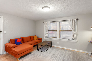 White apartment with wide open spaces, hardwood flooring and modern furniture. Used as a short term rental. 