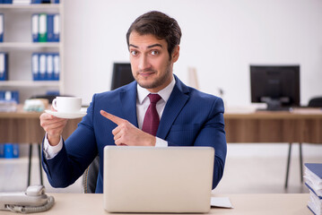 Young male employee drinking coffee during break