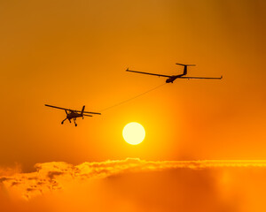 Fototapeta na wymiar Glider towed by ultralight aircraft at sunset
