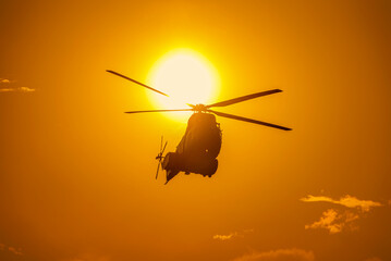 Helicopter in front of the sun at sunset