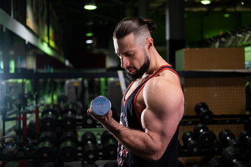 A handsome athletic man with a beard does a bicep exercise in the gym
