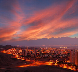 Sunrise panoramic view of Eilat. Glowing town lights at night. Red Sea, Israel. Lights of Aqaba (Jordan) cities on the opposite side of the bay (gulf). Jordan mountains in the misty background