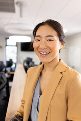 Vertical image of happy asian businesswoman looking at camera in office
