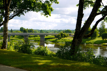 Fototapeta na wymiar Latvian summer nature, view of the river and bridge, trees and city