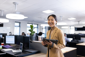 Happy asian businesswoman looking at camera in office